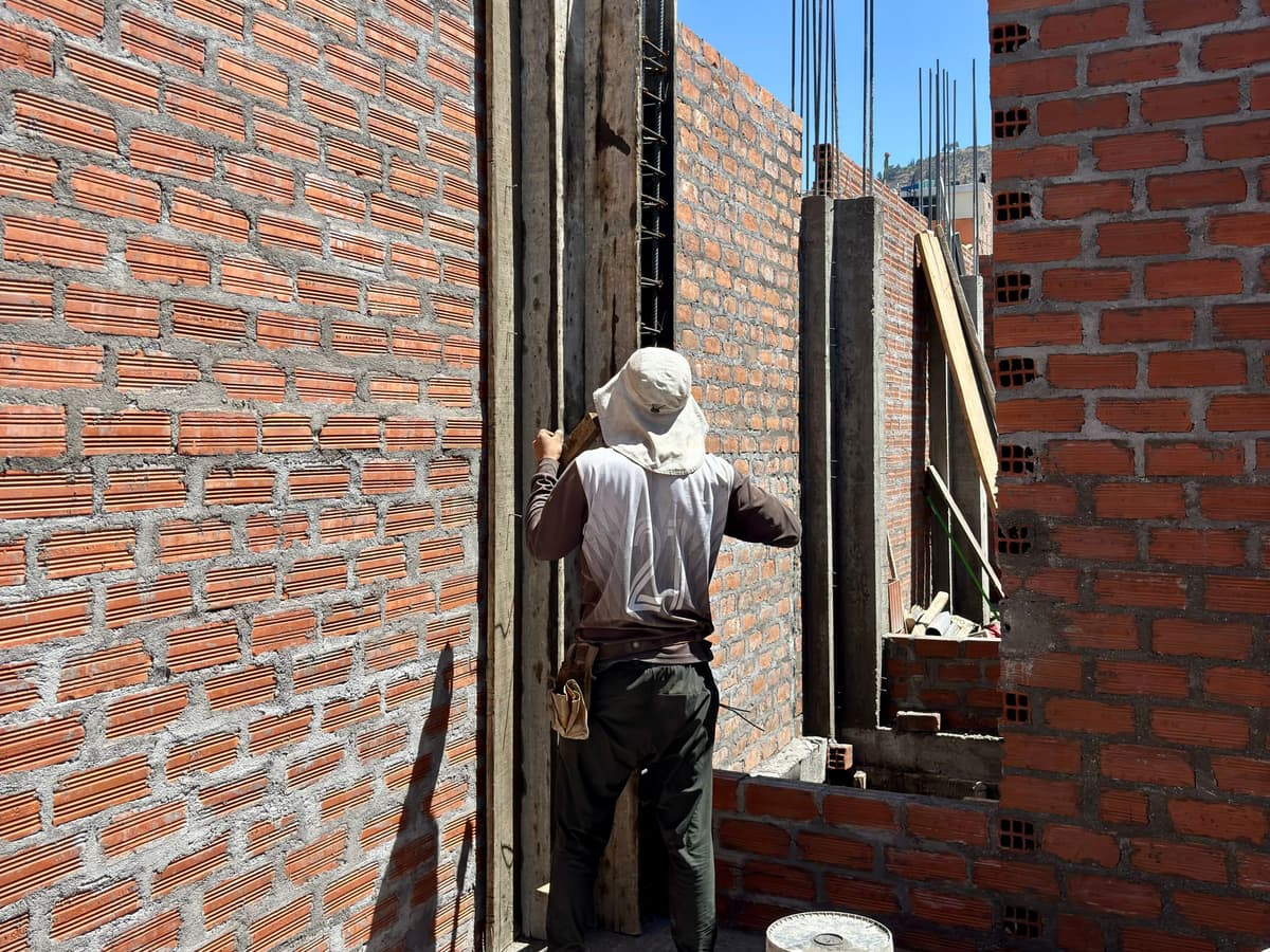 Albañil colocando una formaleta entre paredes de ladrillo en una obra